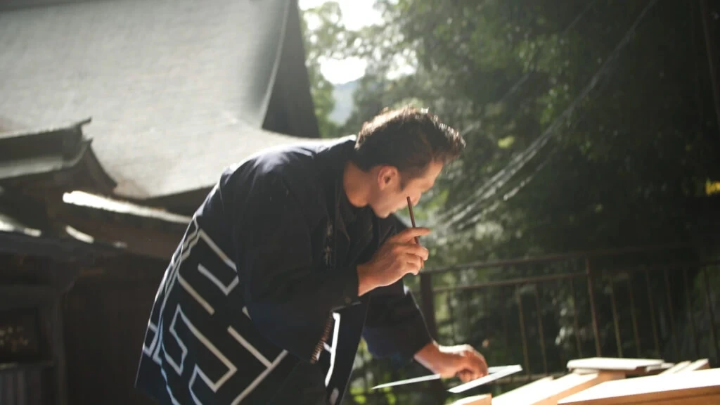 社寺を背景に木材へ墨付けする職人