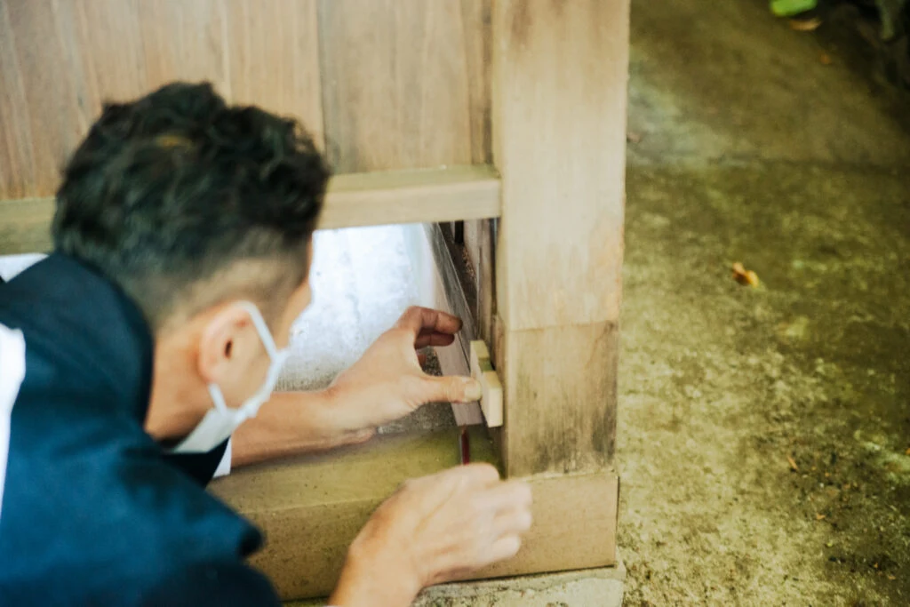 柱の足元を手道具で修復する職人